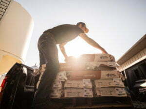 Farmer unloading bags of Golden Harvest corn seed from truck for planting